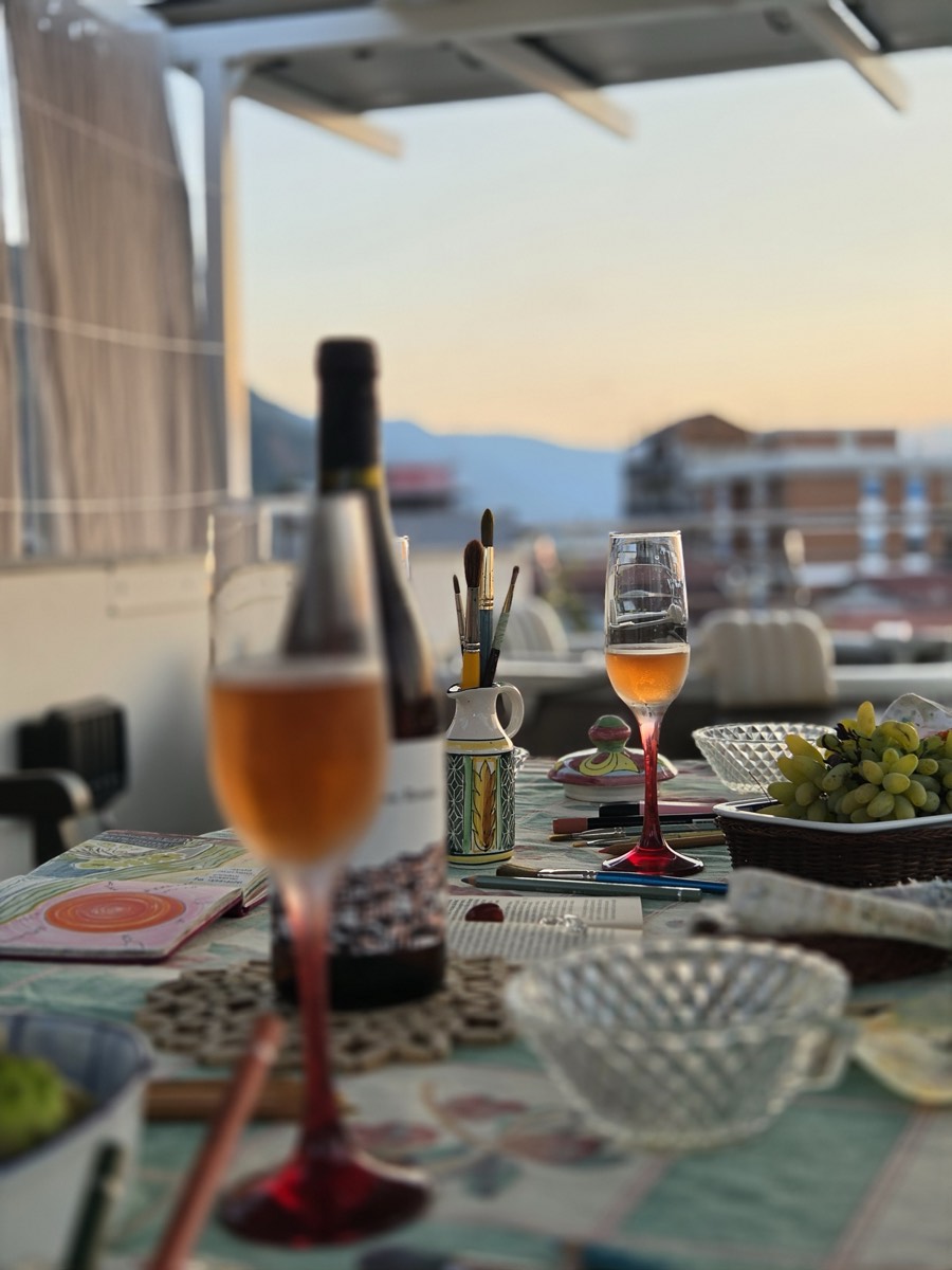 Wine and paintbrushes on a terrace table at sunset