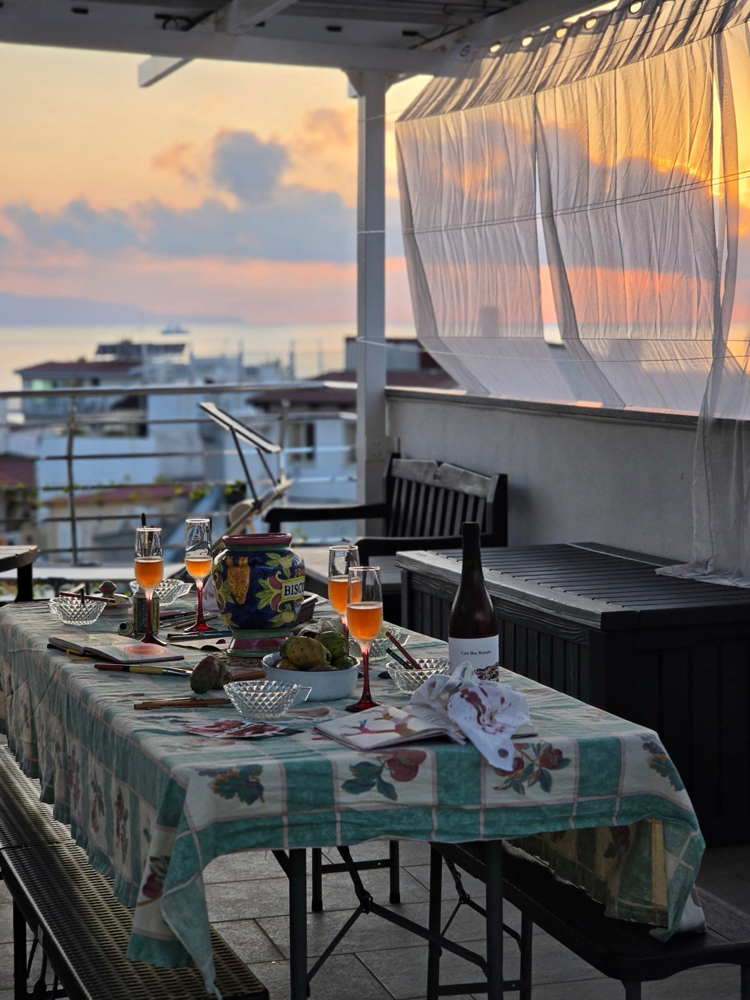 Sunset dinner table with sketchbooks and wine on the veranda terrace overlooking Bagnara and the sea
