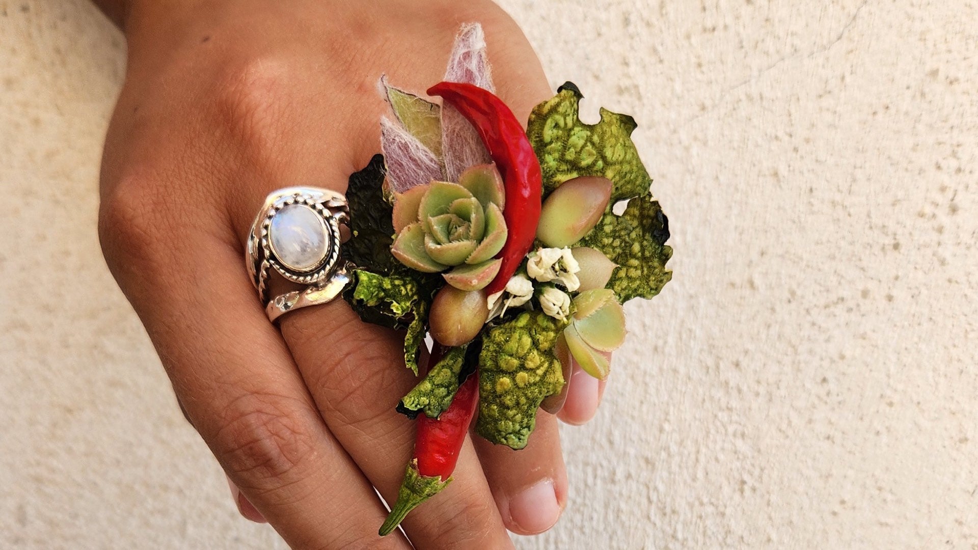 A botanical jewellery piece resting on a hand