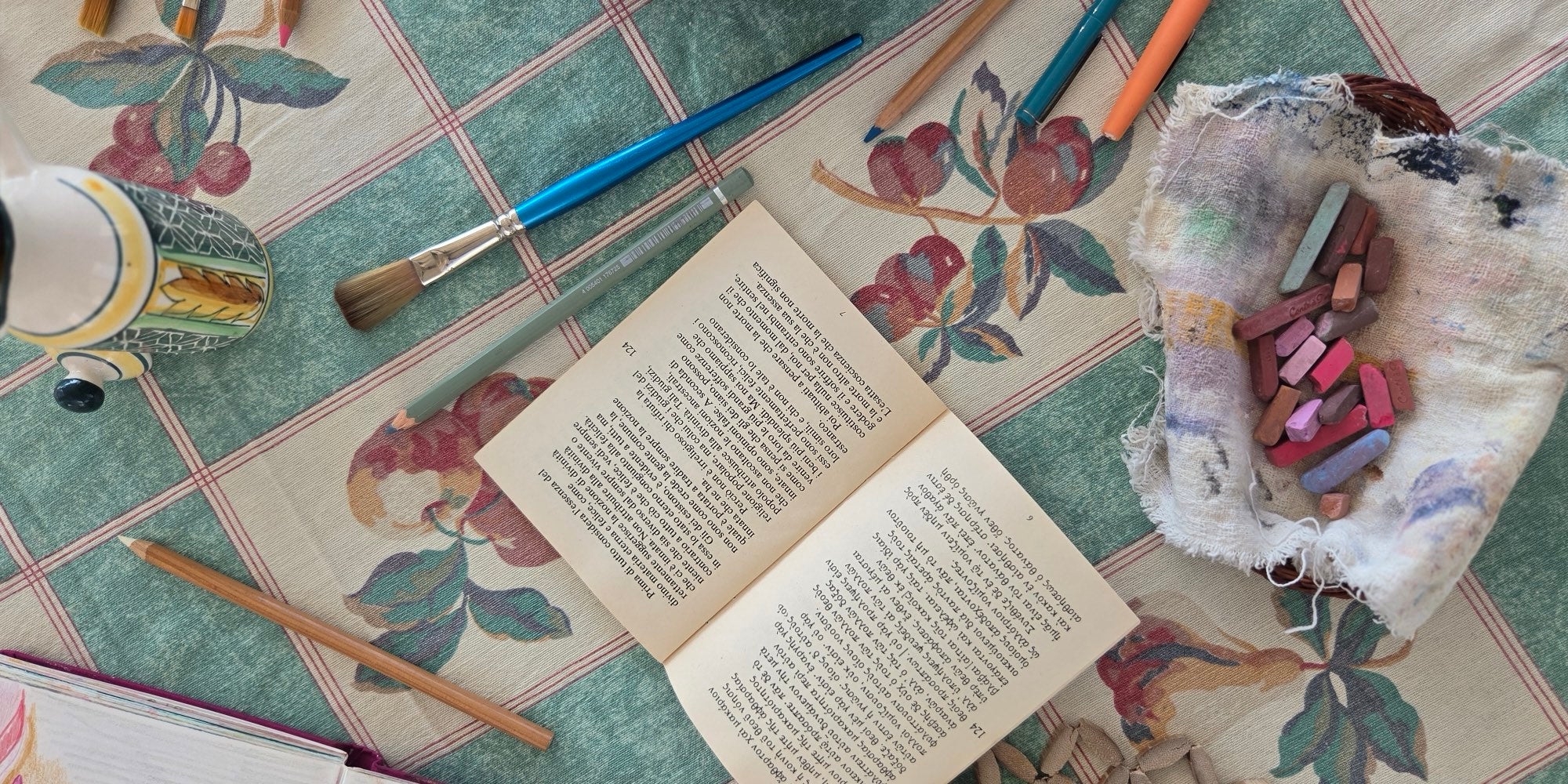A book, brushes and pastels on the workshop table